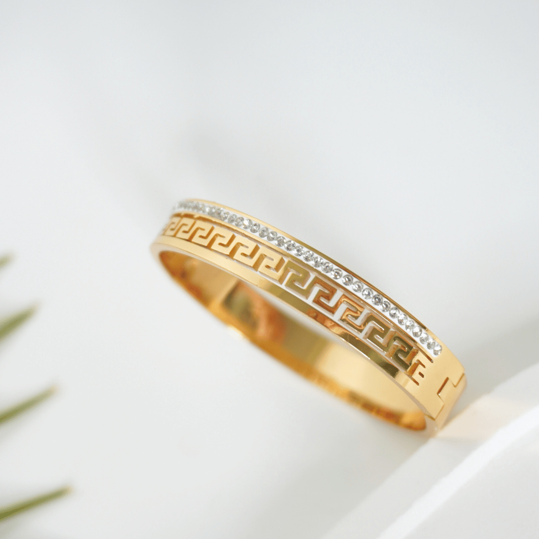 Gold bracelet with intricate design on a white background